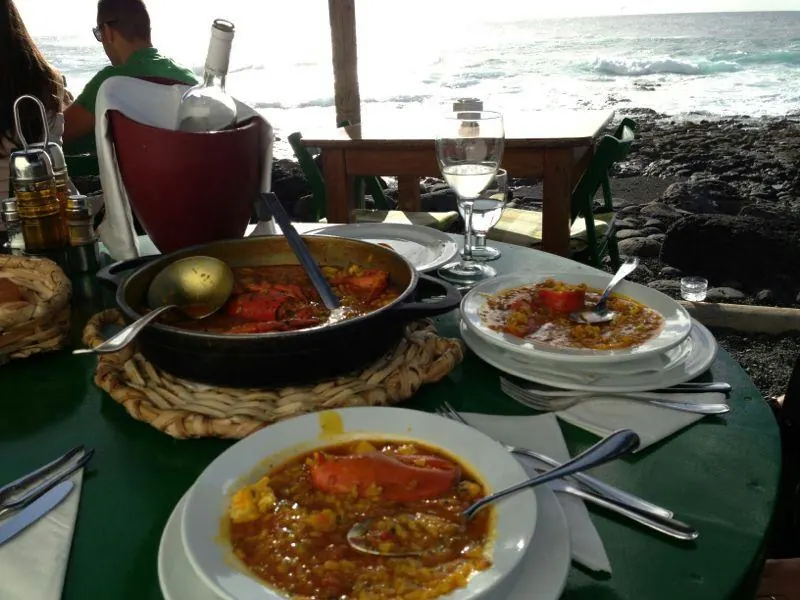 Cazuela de arroz caldoso con bogavante servida en la terraza, con el mar detrás
