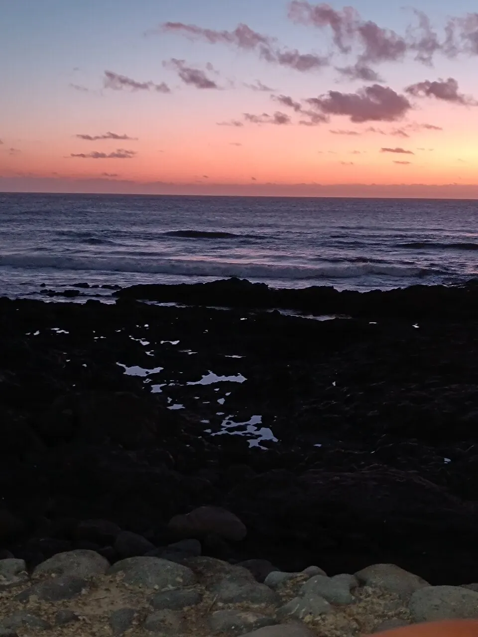 Puesta de sol rosa y naranja sobre el Atlántico vista desde las rocas de El Golfo